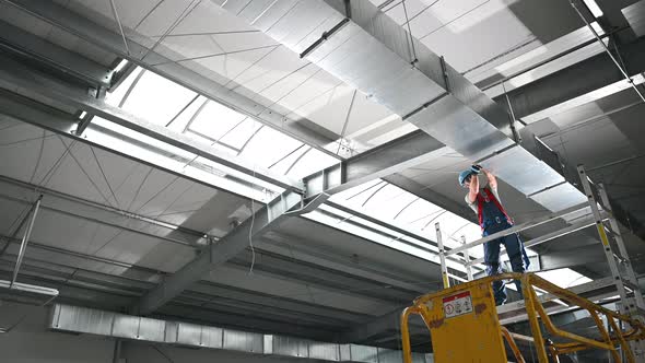 Caucasian Construction Male Worker Installing Industrial Air Ventilation alt