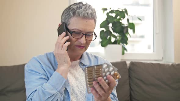 Mature Woman Consults with Her Doctor on the Phone Before Taking the Medicine She Needs