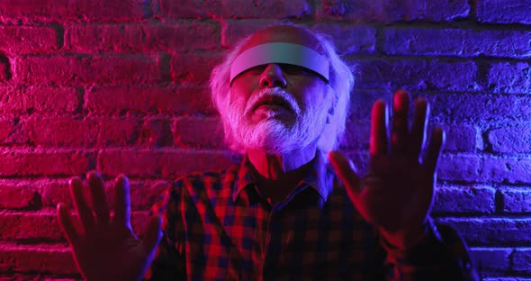 Happy senior man having fun using augmented reality goggles alt