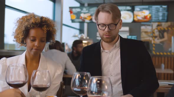 Young Bearded Man Dining with Friends Returning Poor Cooked Dish To Waiter in Mask alt