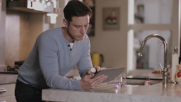 Adult man looking up medicine at home in kitchen