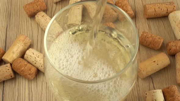Wine is poured into a glass on the background of wine corks. alt