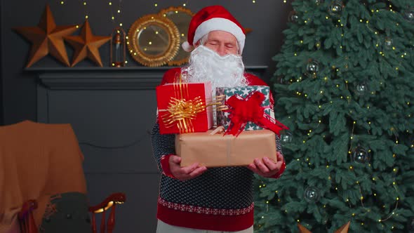 Senior Grandfather Parodies Santa Claus Presenting Christmas Gift Box Holidays Celebration at Home alt