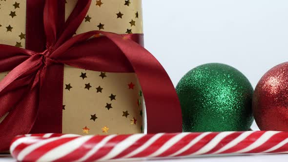 Christmas gift composition with red bow, Christmas tree balls and caramel cane. alt
