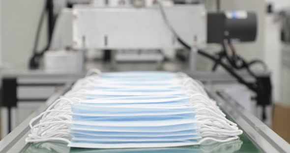 3 Ply Disposable Surgical Mask Coming Out From Machine Into Delivery Mechanism Conveyor. - close up alt