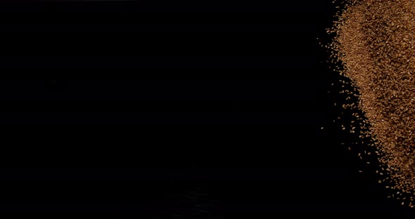 Gold Coloured Sesam, sesamum indicum, Seeds falling against Black Background, slow motion 4K alt
