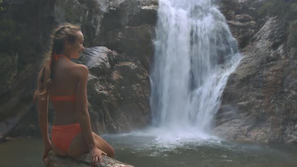 Girl Enjoys Pictorial Nature Against Waterfall alt