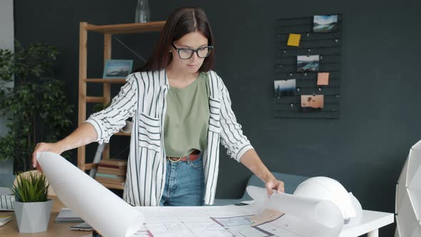Portrait of Freelance Architect Working with Papers at Home Looking at Blueprints and Plans alt