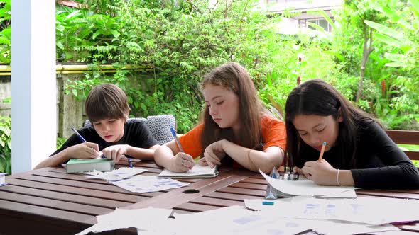 Children, boy and girl, doing homework and drawing together in garden at home.