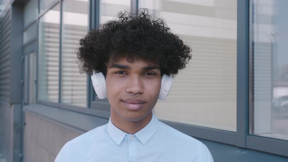 Caucasian Happy Beautiful African American Male in Headphones and Listening to Music Outdoors alt