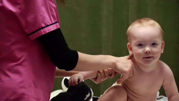 The masseuse gives a massage of shoulder to baby (boy) 04 alt