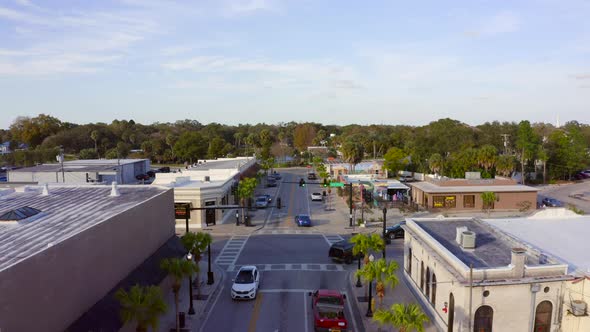Slow Forward Aerial Pan of Cars Driving By Shops and Restaurants on a Main Road alt