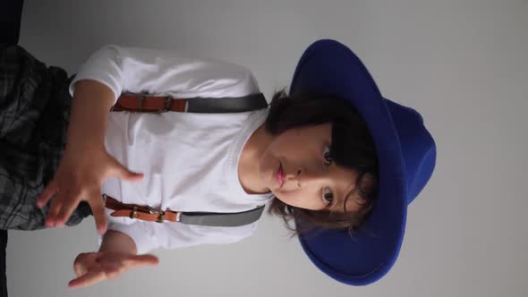 Boy Dances at Home in a Blue Hat with a Brim and a White Tshirt alt