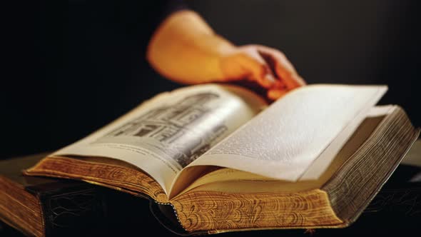 Male hand turning pages of old open book alt