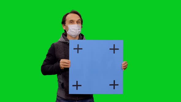 Portrait Of Man In Mask Presenting With Blank Blue Placard