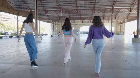 Slomo Pan From Behind of Three Darkhaired Girls Roller Skating alt