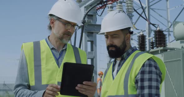 Mature Engineer Showing Data To Bearded Colleague alt