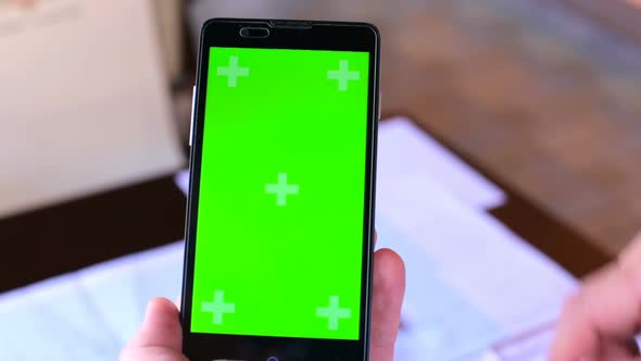 Construction engineer using a smartphone with a green screen looking for information on the internet alt