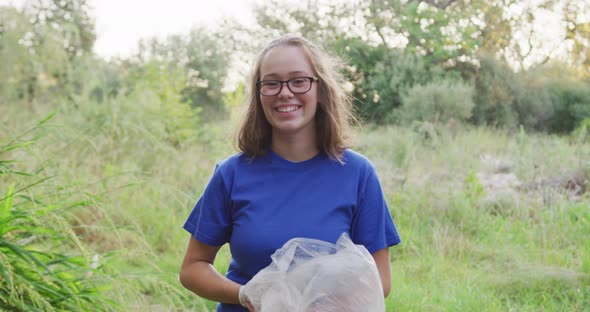 Caucasian woman smiling and looking at camera during river clean-up day alt