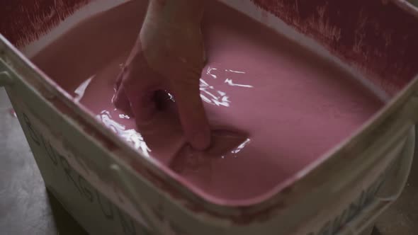 Close up view of female potter dipping pot into paint at pottery studio alt