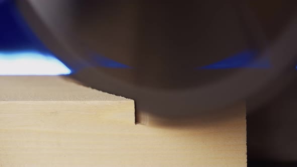 Worker Carpenter Sawing Board with a Circular End Saw in His Carpentry Workshop alt