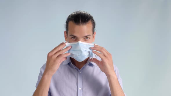 Smiling young man puts on face mask looking at camera, Closeup Studio Shot alt