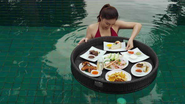 cheerful young woman enjoying with floating food in swimming pool