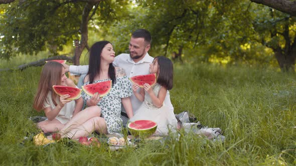 Caucasian Couple with Two Little Daughters Sitting Closely to Each Other at alt
