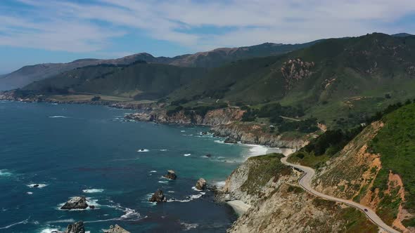 Wide aerial view of a winding curvy highway road along Route 1 on the coast of Big Sur California wi alt