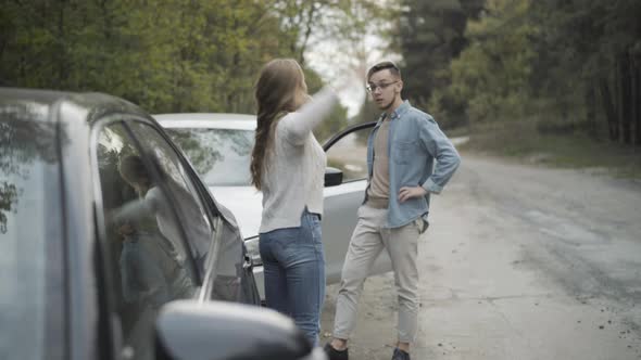 Young Stressed Man and Woman Yelling and Gesturing on Roadside alt
