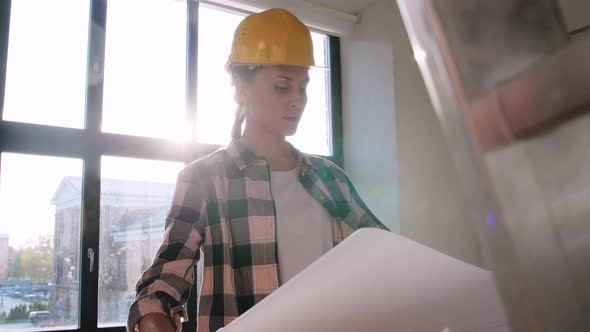 Woman in Helmet with Blueprint at New Home