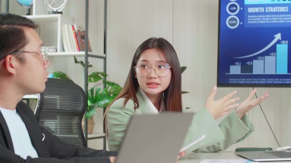 Young Asian Team Have Meeting In A Conference Room. They Share Opinions, Statistics Show On Tv alt