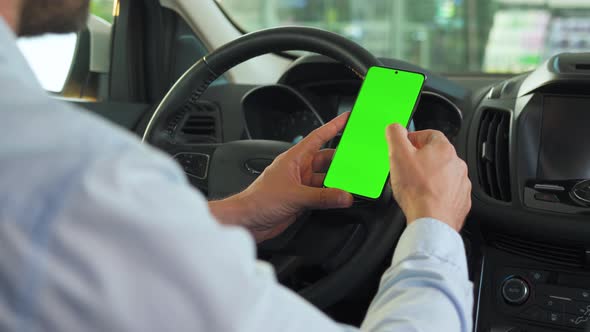 Driver Using a Smartphone Inside the Car. Chromakey Smartphone with Green Screen. Auto Navigation alt