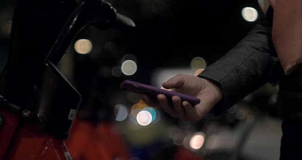 Tourist Woman Take Electric Kick Scooter or Bike Bicycle in Sharing Parking Lot at Night Phone alt