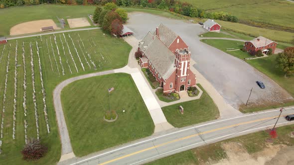A reverse aerial establishing shot of a typical red brick church in the Pennsylvania countryside in alt