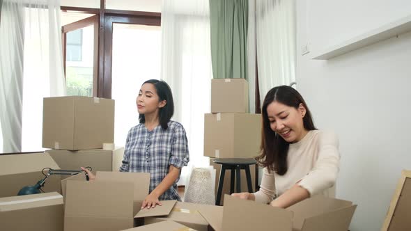 Happy asian women LGBT lesbian couple holding boxes entering new modern house alt