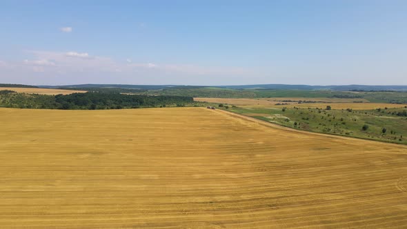 Aerial View of Cargo Trucks on Dirt Road Between Agricultural Wheat Fields alt