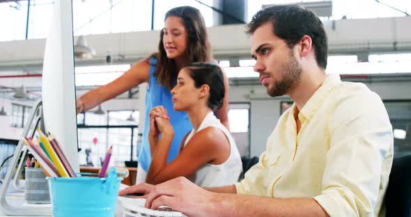 Smiling businessman working on computer in office alt