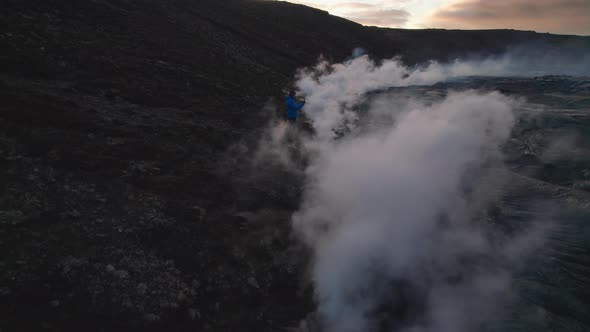 Drone Towards Man Texting Erupting Fagradalsfjall Volcano alt