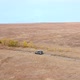 Offroad Car Driving on Country Road Along Yellowed Fields in Village. Drone Aerial View SUV Vechie