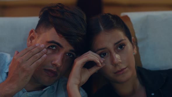 Attractive cheerful young caucasian couple crying while watching film in movie theater alt