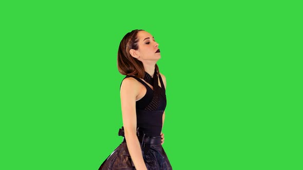 Cyberpunk Girl in Leather Skirt and with Gun on Belt Walks on a Green Screen Chroma Key