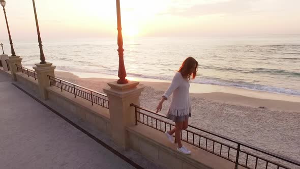 Aerial Footage Skinny Longhaired Girl Walking Along Parapet of Embankment Keeping Balance Looking alt