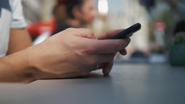 Close  Up Shot of Man's Hands Use Modern Mobile Phone While Sitting at Outdoor Cafe alt