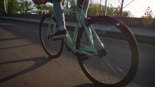 Young Stylish Woman Cyclist Enjoying Fixed Gear Bike Riding Outdoors at Sunrise Near the Sea Close alt