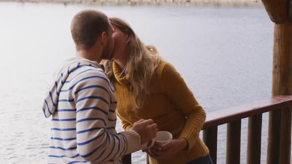 Caucasian couple spending time at home together, kissing outside the cabin alt