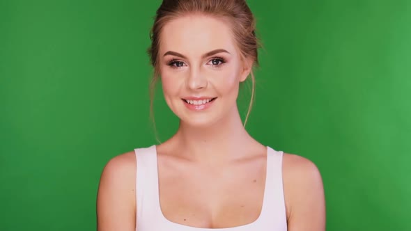 Attractive Female Looking To the Camera and Smiling Isolated on Green alt