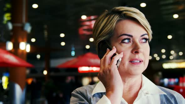 Businesswoman talking on mobile phone in waiting area alt