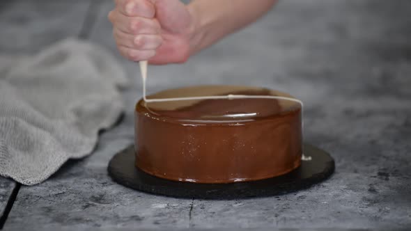 Female Confectioner Decorating Tasty Mousse Cake with Melted White Chocolate