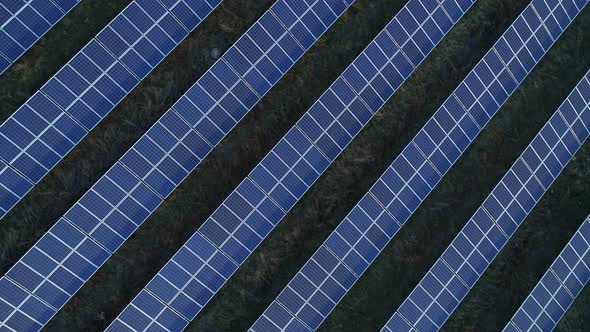 Aerial Drone Footage. Flight Over Solar Panel Farm Top Down View at Sunset. alt